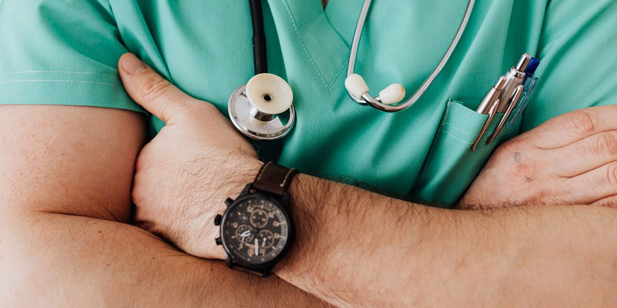 Medico con braccia conserte e stetoscopio attorno al collo.