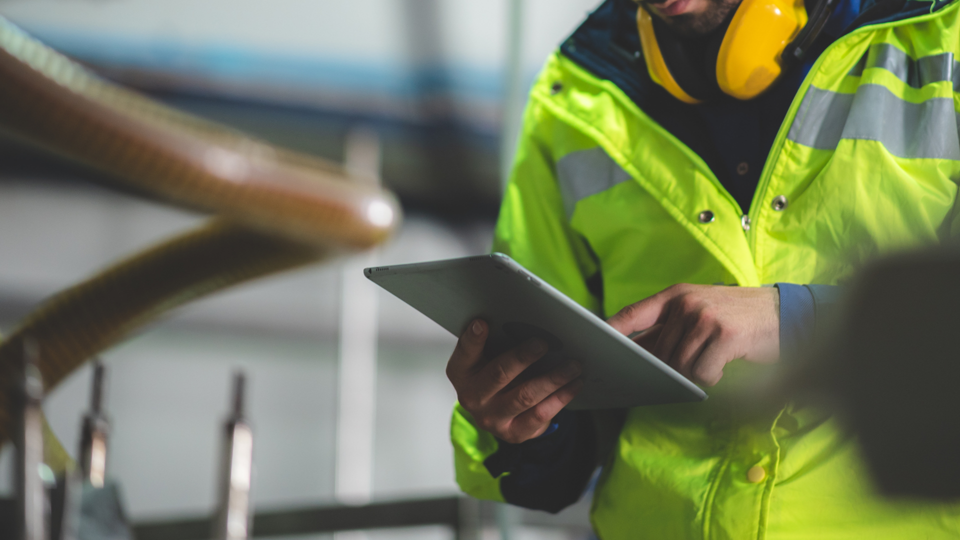 Tecnico in abbigliamento ad alta visibilità utilizza un tablet in ambiente industriale – immagine rappresentativa del blog di Net srl dedicato alla sicurezza sul lavoro.