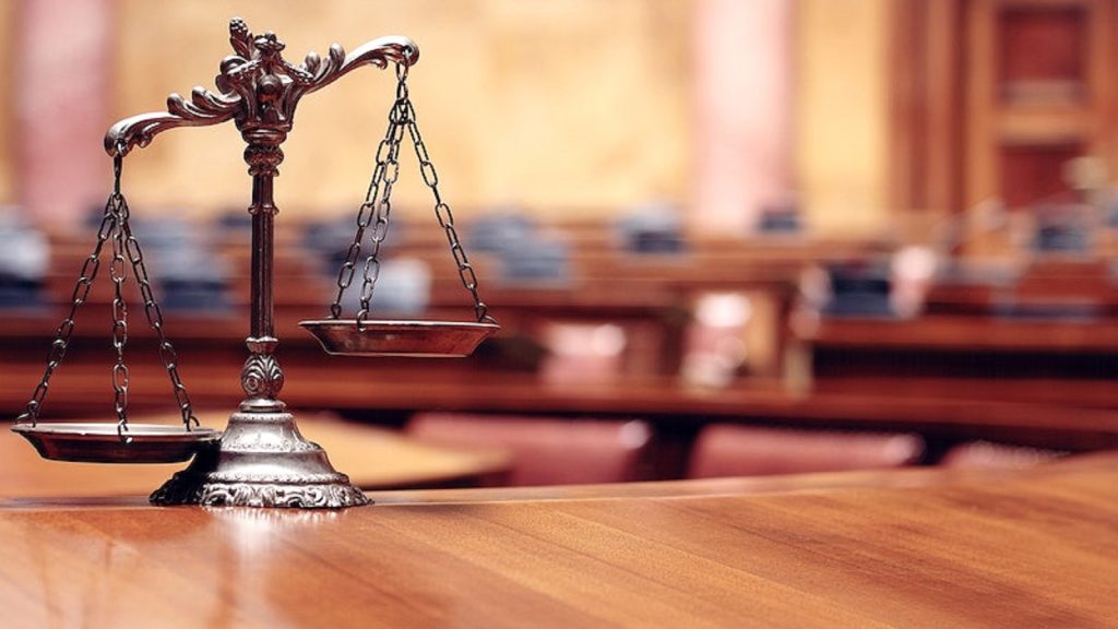 Bilancia della giustizia in un’aula di tribunale, simbolo del riconoscimento dei diritti dei lavoratori in caso di stress lavoro-correlato.
